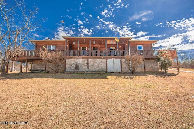 back of house with stone siding, a lawn, a wooden deck, and faux log siding