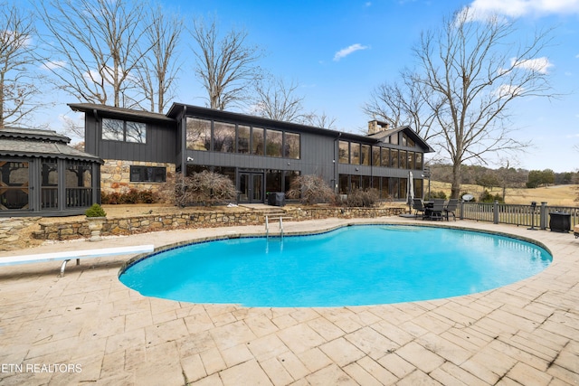 view of swimming pool featuring a patio area, fence, a sunroom, and a fenced in pool