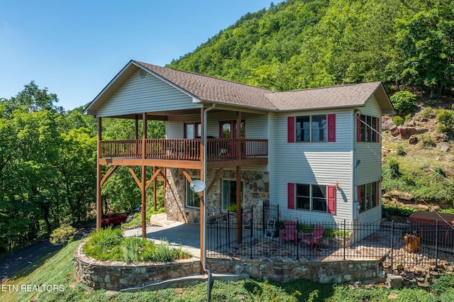 954 Pawnee Ct, Sevierville, TN 37876 - back of property with a view of trees, a patio, a shingled roof, stone siding, and a carport