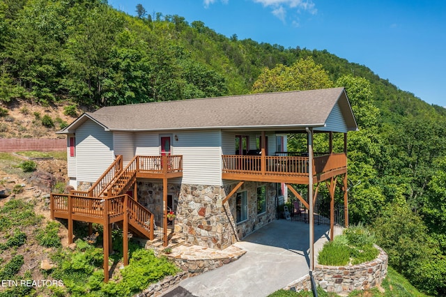 954 Pawnee Ct, Sevierville, TN 37876 - rear view of property featuring stone siding, a wooded view, a deck, concrete driveway, and stairway