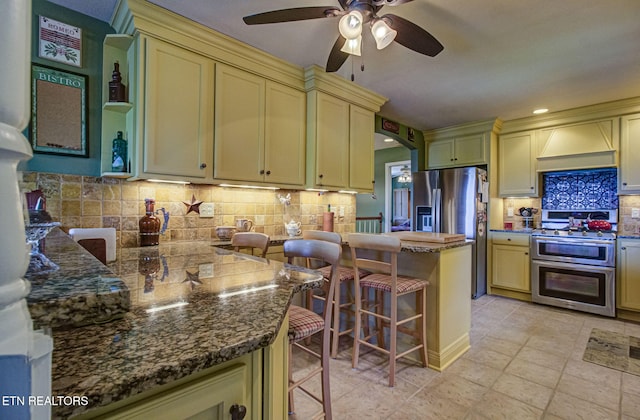 954 Pawnee Ct, Sevierville, TN 37876 - kitchen with cream cabinets, a kitchen bar, stainless steel appliances, ceiling fan, and custom range hood