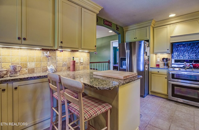 954 Pawnee Ct, Sevierville, TN 37876 - kitchen with stainless steel appliances, cream cabinets, custom exhaust hood, arched walkways, and decorative backsplash