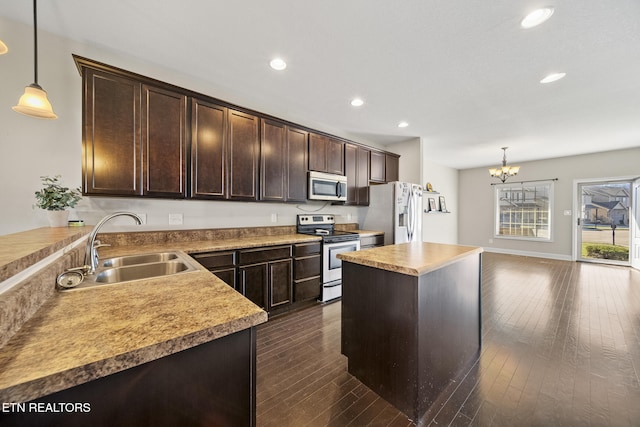 kitchen featuring dark brown cabinetry, a sink, hanging light fixtures, appliances with stainless steel finishes, and dark wood-style floors