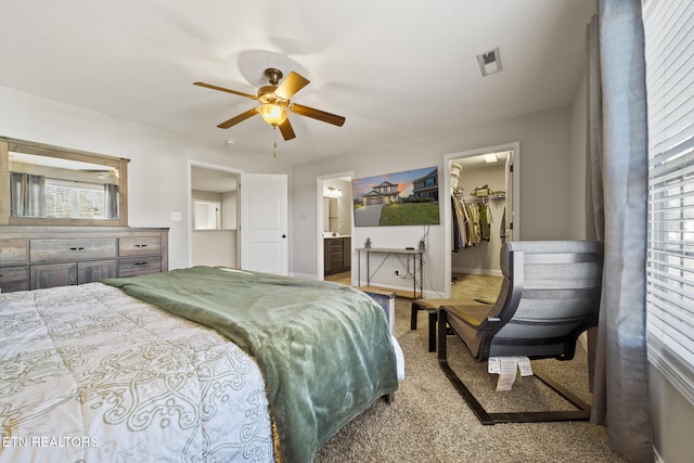 bedroom with a walk in closet, visible vents, ensuite bathroom, ceiling fan, and baseboards