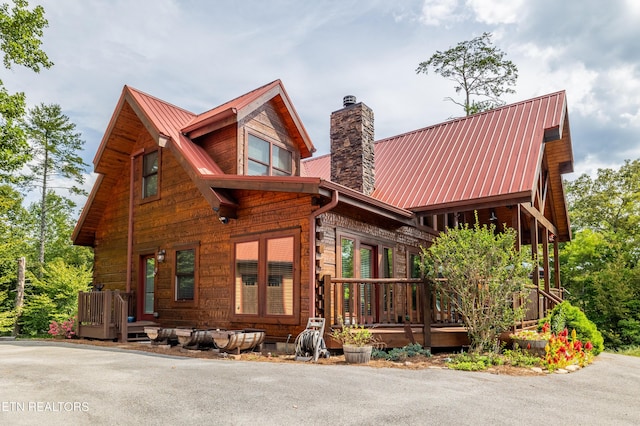 view of front of property featuring covered porch, metal roof, a chimney, and crawl space