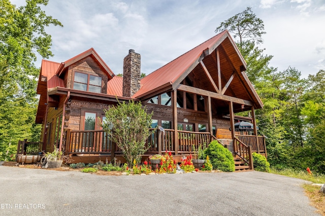 view of front of property featuring metal roof, a chimney, and a porch