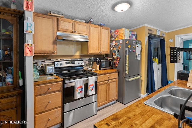 kitchen featuring stainless steel appliances, a sink, a textured ceiling, independent washer and dryer, and under cabinet range hood