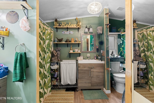 bathroom with a textured ceiling, toilet, wood finished floors, visible vents, and ornamental molding