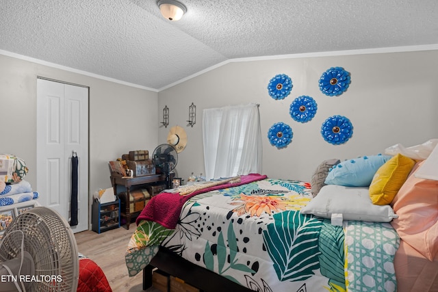 bedroom with lofted ceiling, a closet, wood finished floors, and a textured ceiling