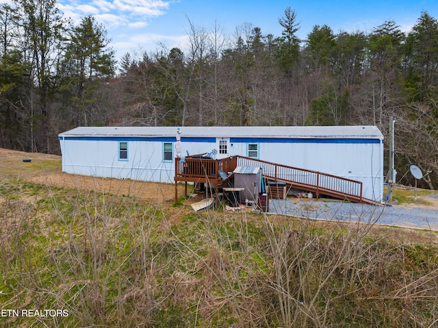 rear view of house featuring a view of trees and a wooden deck