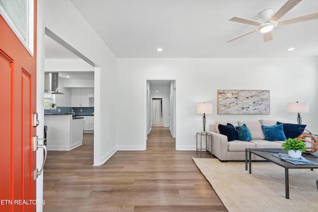 living room featuring a ceiling fan, recessed lighting, baseboards, and wood finished floors