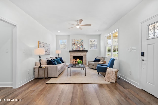 living room with a fireplace, ceiling fan, wood finished floors, and plenty of natural light