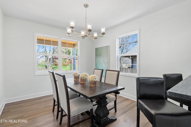dining room with an inviting chandelier, baseboards, and wood finished floors