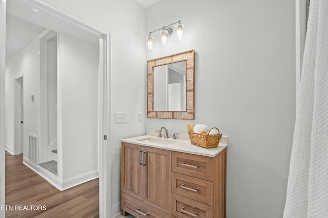 bathroom with baseboards, visible vents, wood finished floors, and vanity