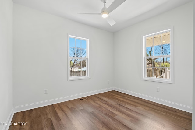 spare room with baseboards, visible vents, ceiling fan, and wood finished floors