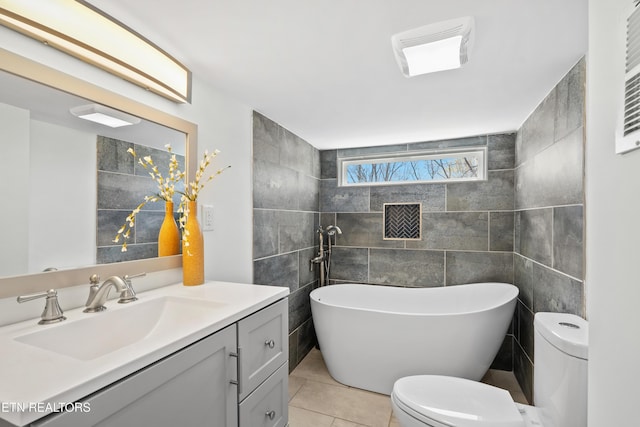 full bathroom with tile walls, toilet, tile patterned floors, vanity, and a freestanding bath