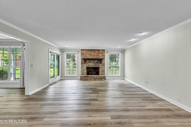 unfurnished living room with crown molding, a fireplace, plenty of natural light, and wood finished floors