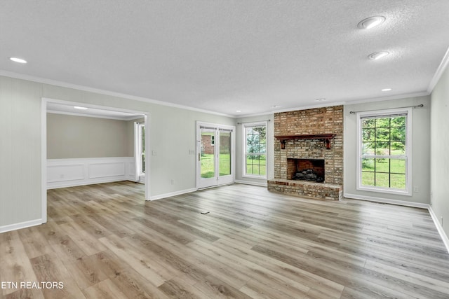 unfurnished living room with crown molding, a fireplace, a textured ceiling, and light wood finished floors