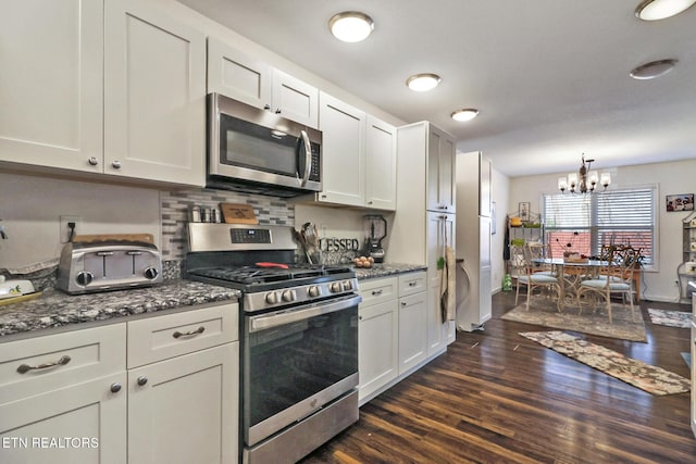 kitchen with dark wood-type flooring, a notable chandelier, backsplash, stainless steel appliances, and white cabinets