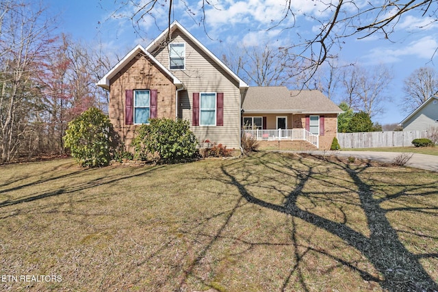 view of front of house featuring a front yard, covered porch, fence, and brick siding