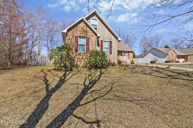 view of front of property featuring a front yard, fence, and brick siding