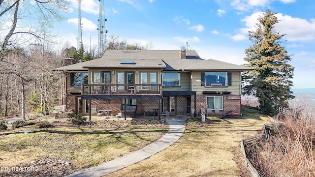 view of front facade with a patio area, brick siding, a chimney, and a front lawn