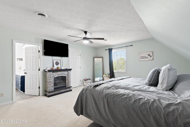 carpeted bedroom featuring a brick fireplace, visible vents, vaulted ceiling, and a textured ceiling