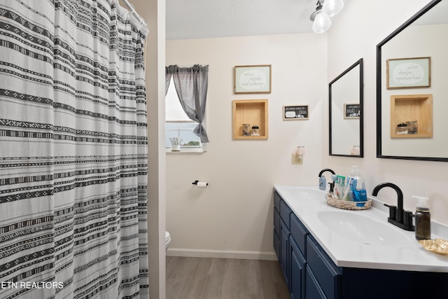 bathroom with wood finished floors, a sink, toilet, and baseboards