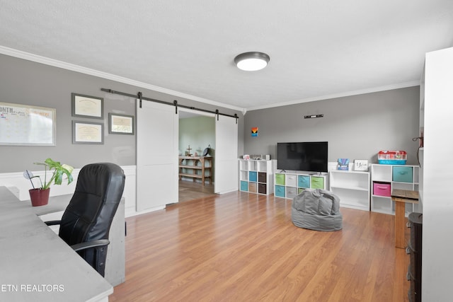 office space with a textured ceiling, a barn door, wood finished floors, and crown molding