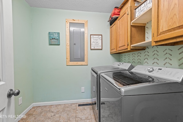 washroom with cabinet space, electric panel, baseboards, a textured ceiling, and washing machine and dryer