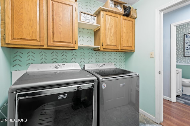 clothes washing area with washer and clothes dryer, cabinet space, and baseboards