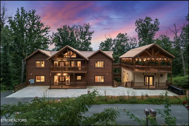 back of property with metal roof, a patio, and a balcony