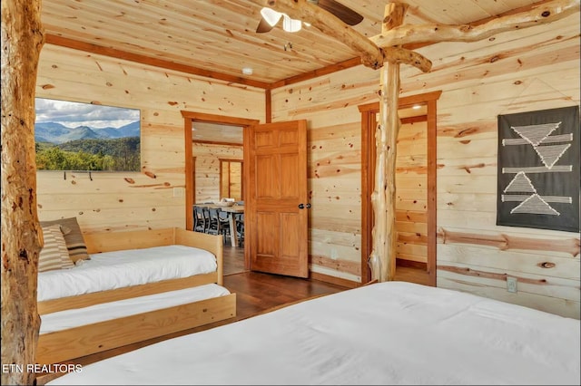 bedroom with wooden ceiling, wood finished floors, a mountain view, and wooden walls