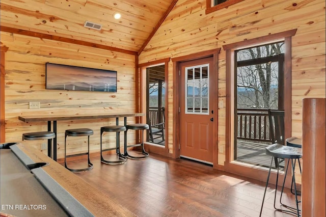 foyer featuring lofted ceiling, wooden ceiling, wood walls, wood finished floors, and visible vents