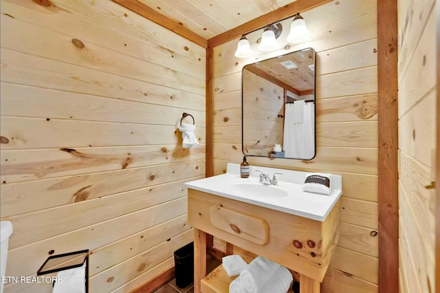 bathroom with vanity and wooden walls