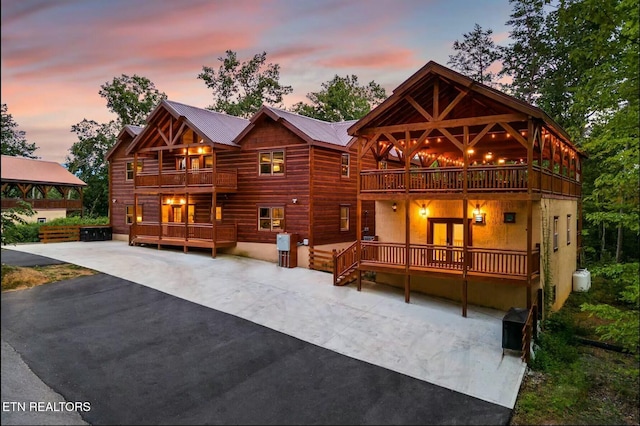 back of property at dusk with a balcony, a patio area, and metal roof