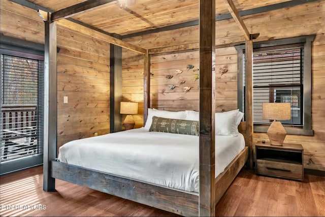 bedroom with wooden ceiling, wooden walls, and wood finished floors