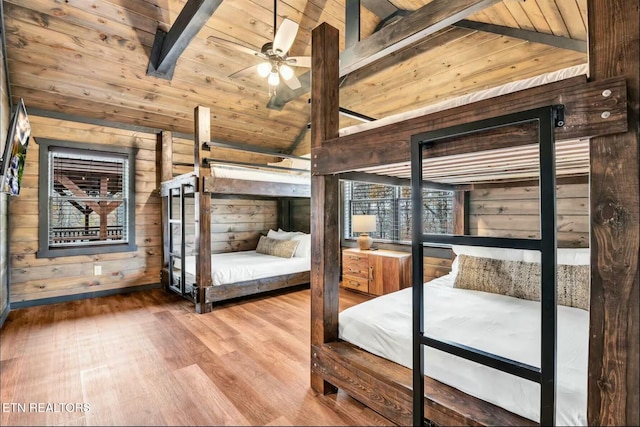 unfurnished bedroom with lofted ceiling with beams, wood finished floors, wood ceiling, and wooden walls