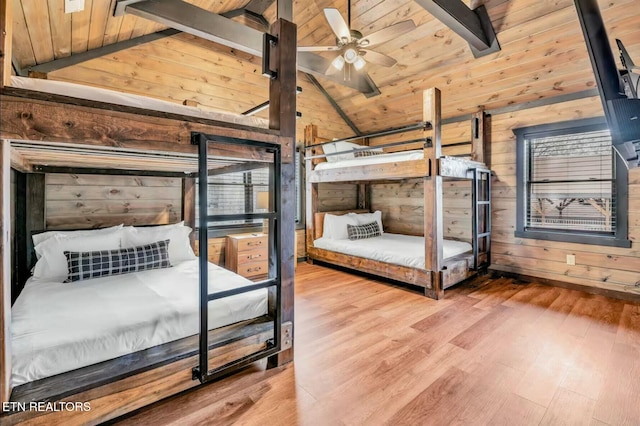 bedroom featuring lofted ceiling with beams, wood ceiling, wooden walls, and wood finished floors