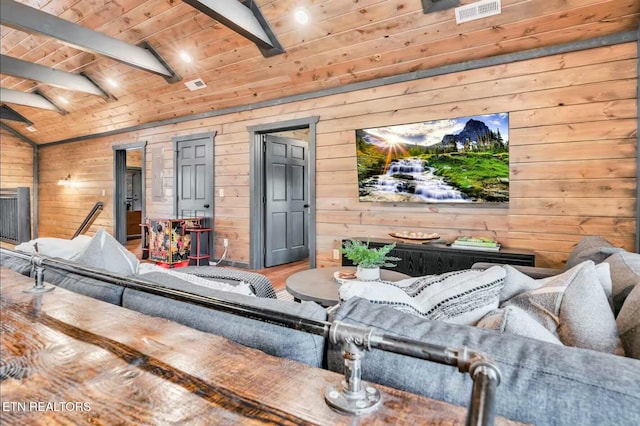 living room with visible vents, lofted ceiling with beams, wood ceiling, wood finished floors, and wood walls