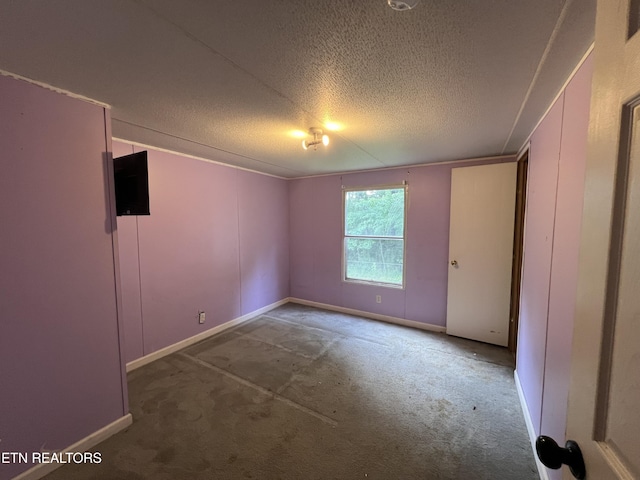 empty room featuring a textured ceiling, carpet, and baseboards