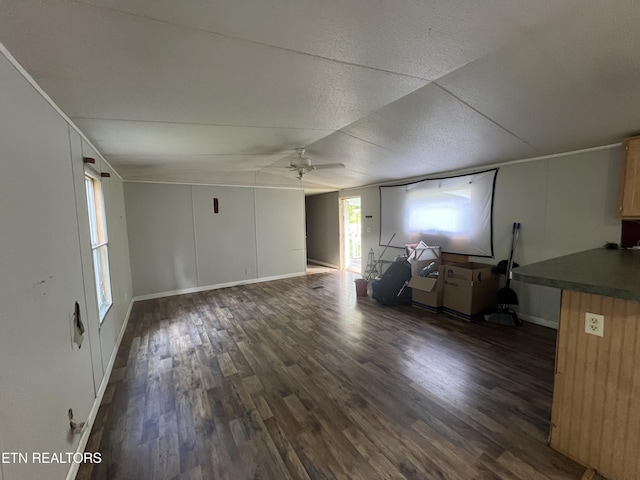 unfurnished living room with ceiling fan, dark wood finished floors, and a textured ceiling