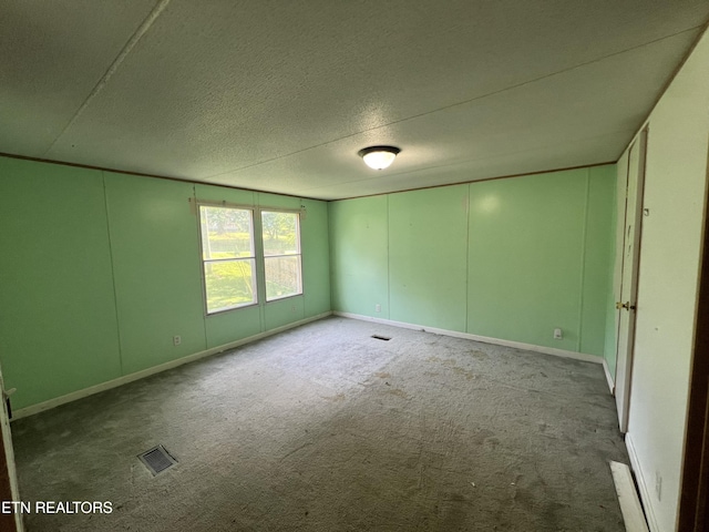 unfurnished room with carpet, visible vents, and a textured ceiling