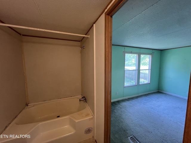 bathroom with baseboards, tub / shower combination, and a textured ceiling