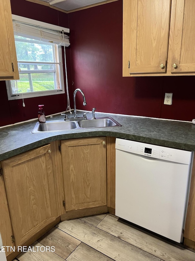 kitchen with dark countertops, light wood finished floors, white dishwasher, and a sink