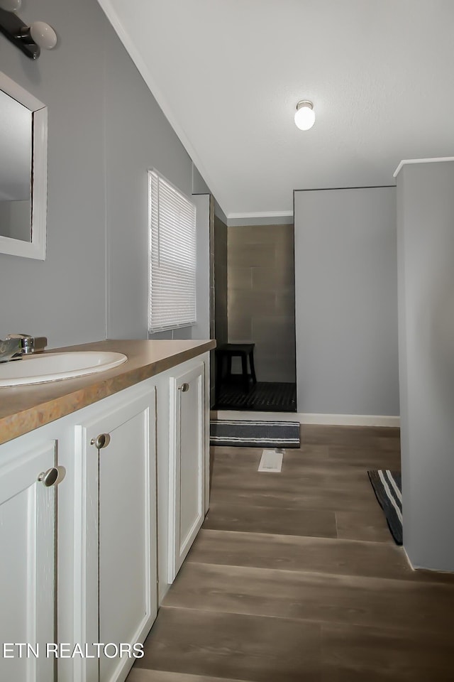 kitchen featuring butcher block counters, ornamental molding, white cabinetry, a sink, and wood finished floors