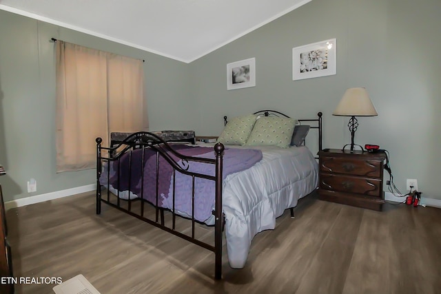 bedroom with lofted ceiling, crown molding, wood finished floors, and baseboards