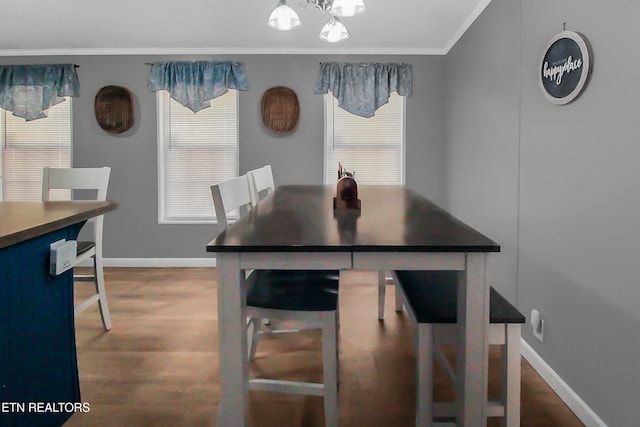 dining area featuring plenty of natural light, baseboards, crown molding, and wood finished floors