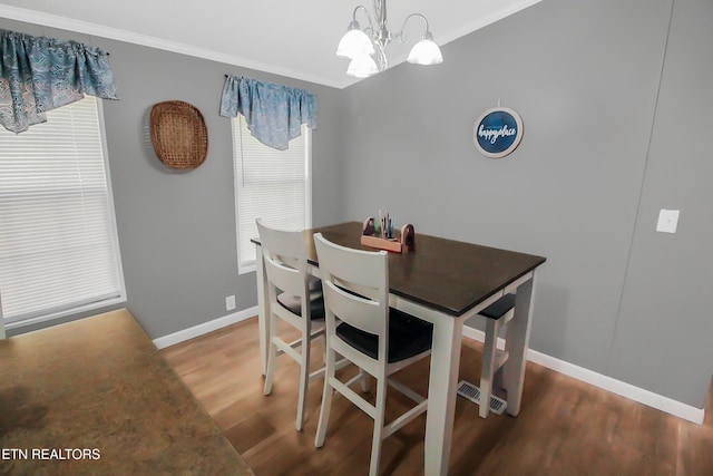 dining room with baseboards, ornamental molding, a chandelier, and wood finished floors