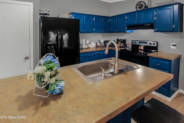 kitchen with blue cabinetry, black fridge, and stainless steel electric range